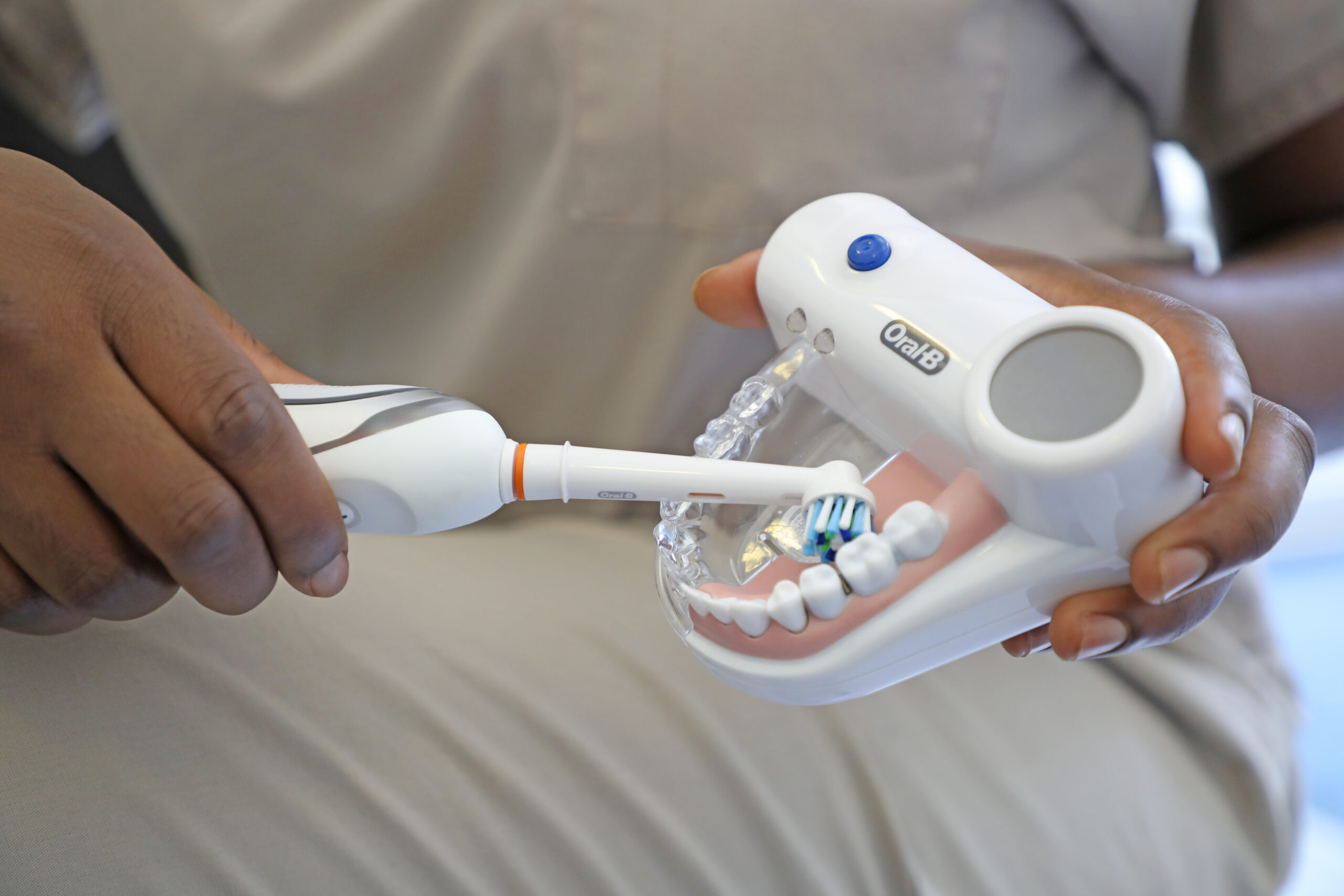 Photo of Dr Ope Sodeinde: Showing how to do Pre-Treatment Dental Care for General Dentistry holding an Electric Toothbrush and a Oral-B Dental Example Set of Teeth