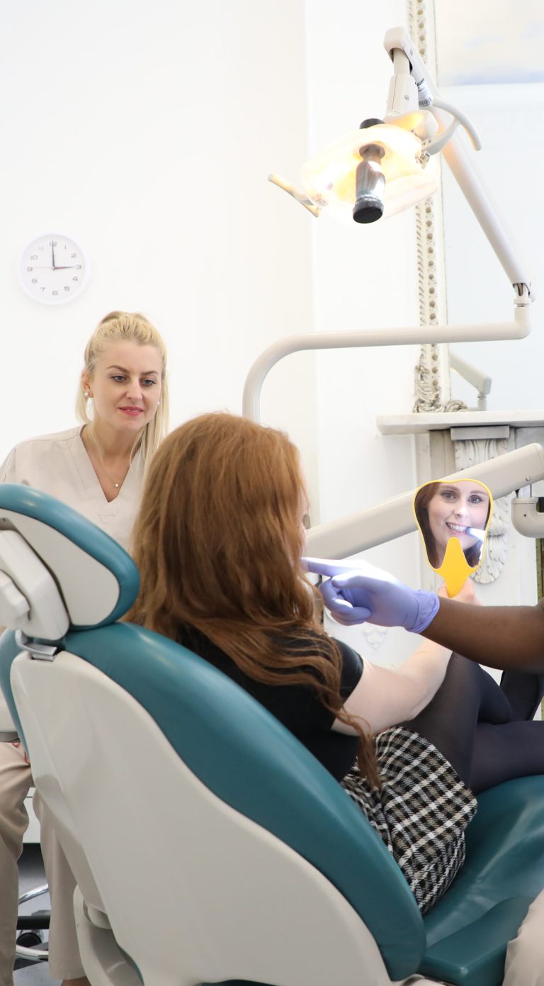 Cosmetic Dentistry patient at our clinic London Dental Specialists in London, UK looking at the benefits for their new Cosmetic Dentistry while sitting in their dental treatment procedure chair and looking into a mirror