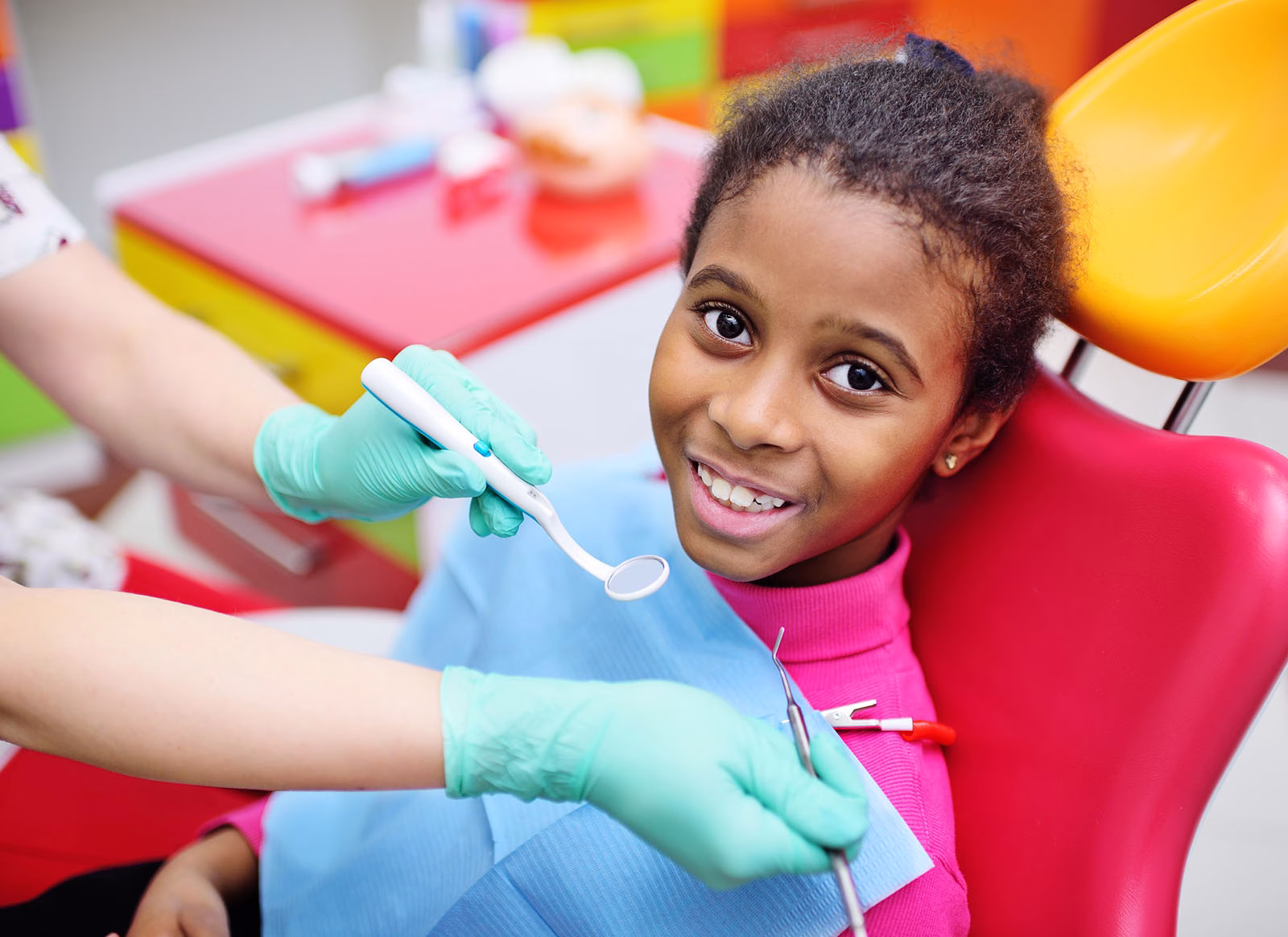 A young patient smiling during a check-up in a child-friendly dental chair