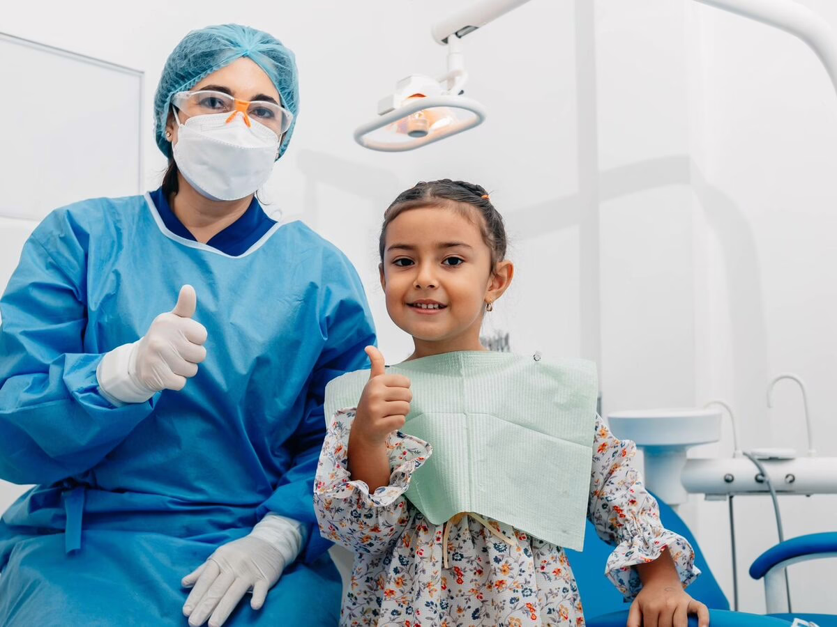 A child giving a thumbs up in the dental chair