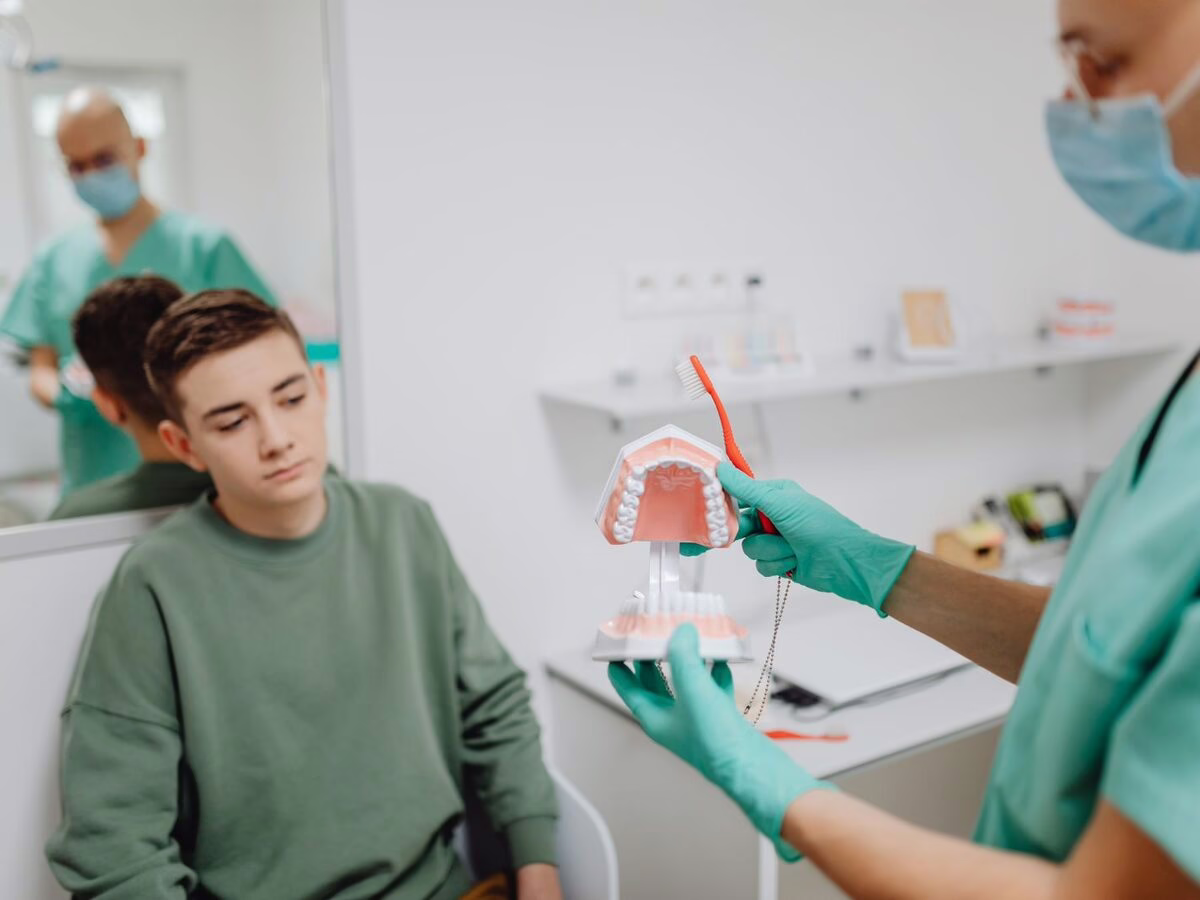 A teenager with a clinician and a dental model