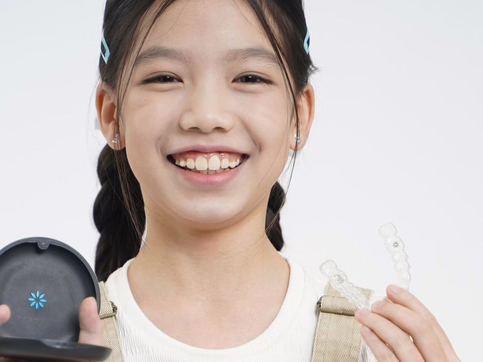 A girl holding a clear aligner and its case