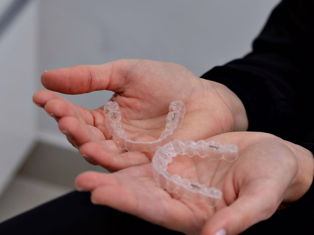 Hands holding clear aligners