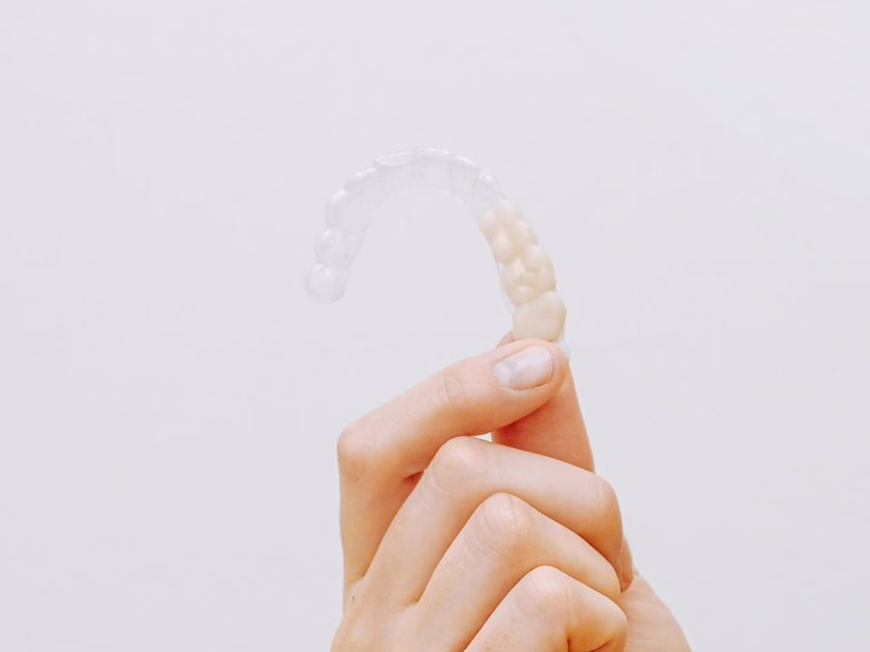 A hand holding a clear aligner