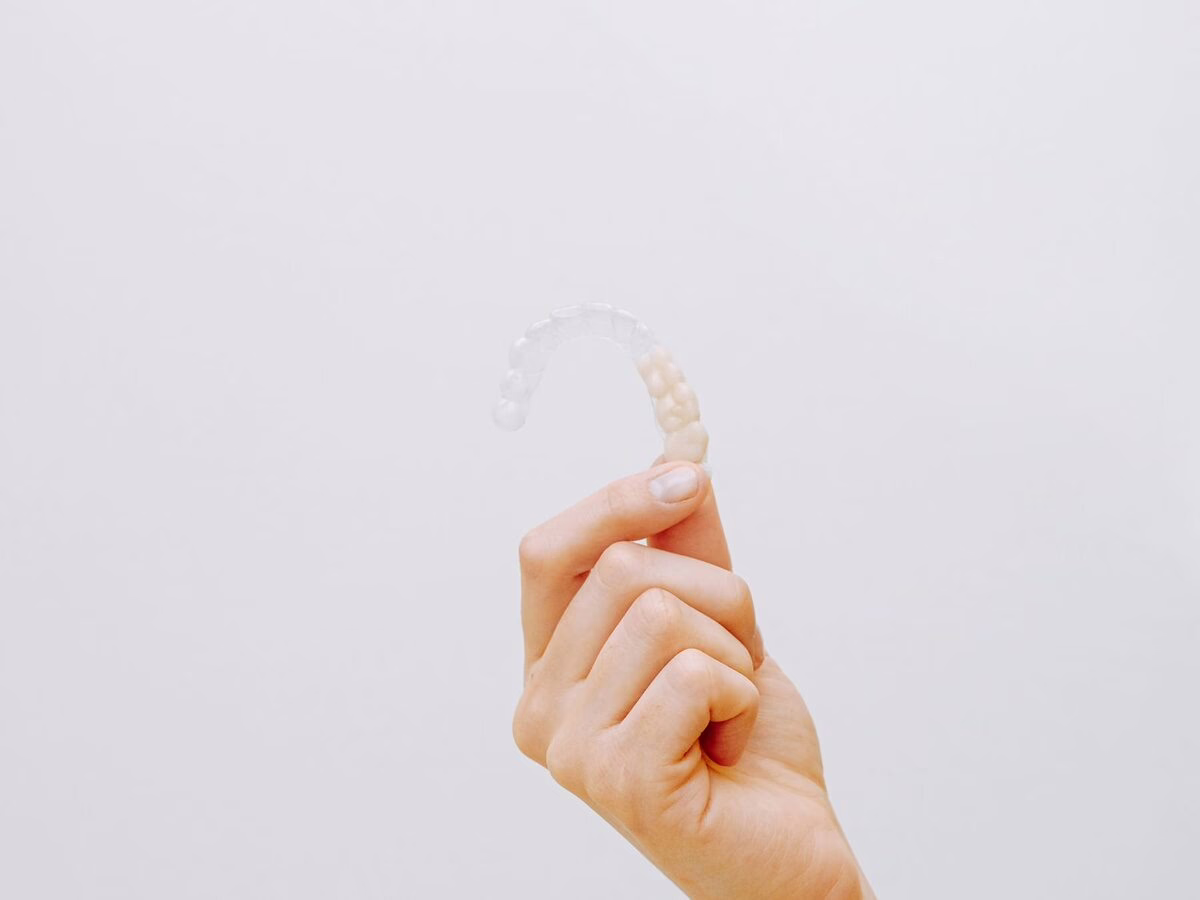 A hand holding a clear aligner