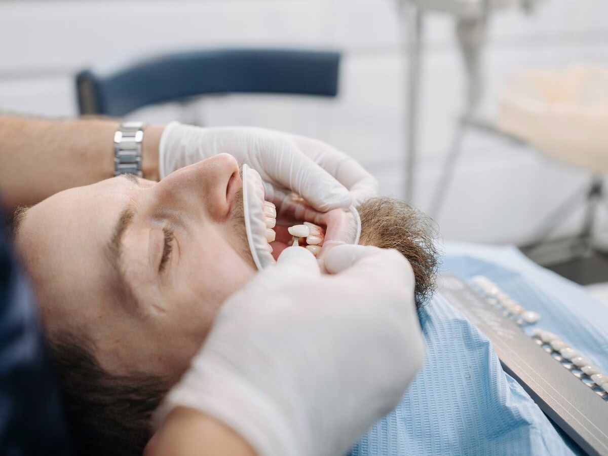 An older patient holding a denture in the dental chair