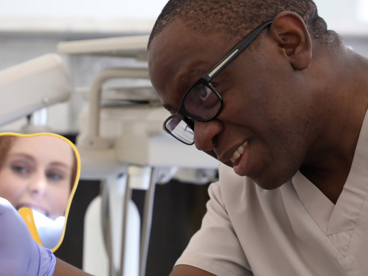Dr Ope Sodeinde showing a patient her smile in a hand mirror