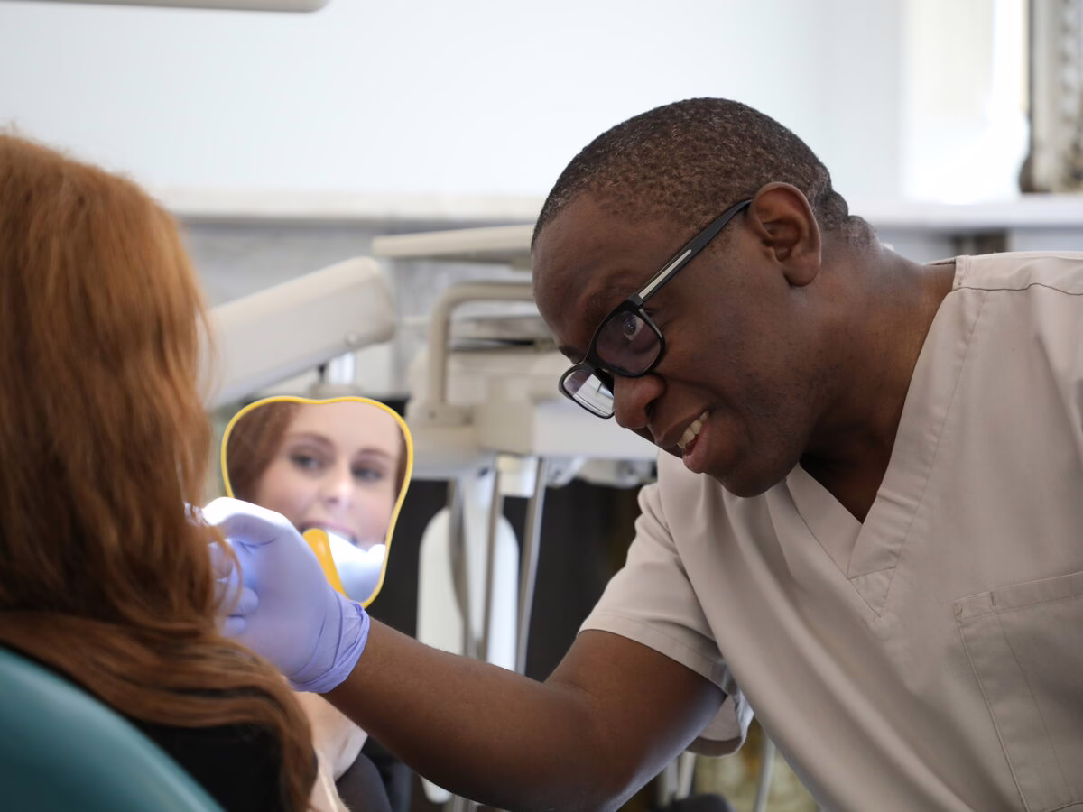 Dr Ope Sodeinde showing a patient her smile in a hand mirror