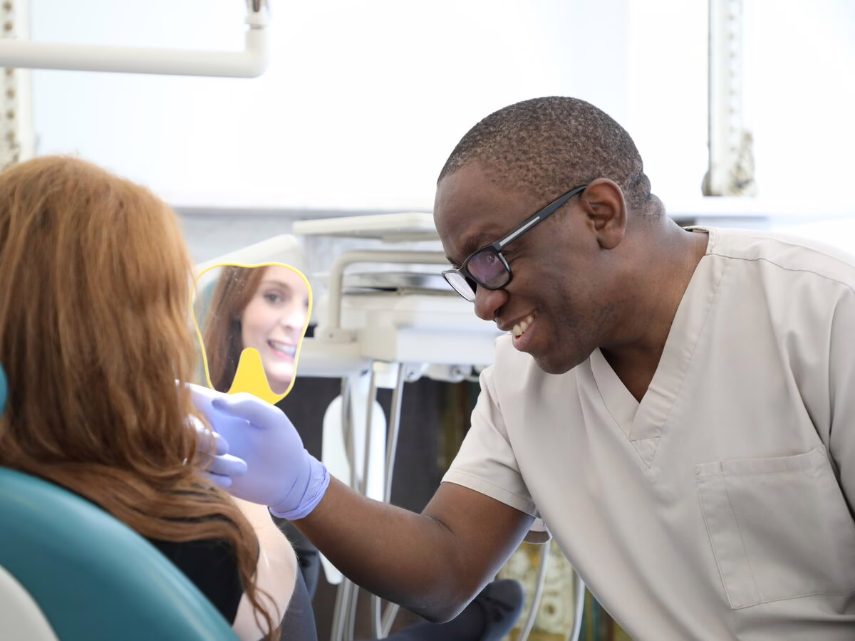 Dr Ope Sodeinde showing a patient her smile in a hand mirror