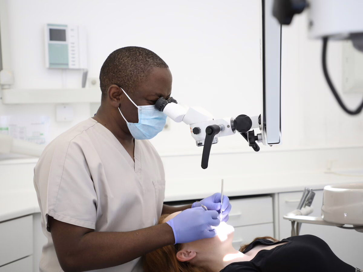Dr Ope Sodeinde treating a patient with magnification