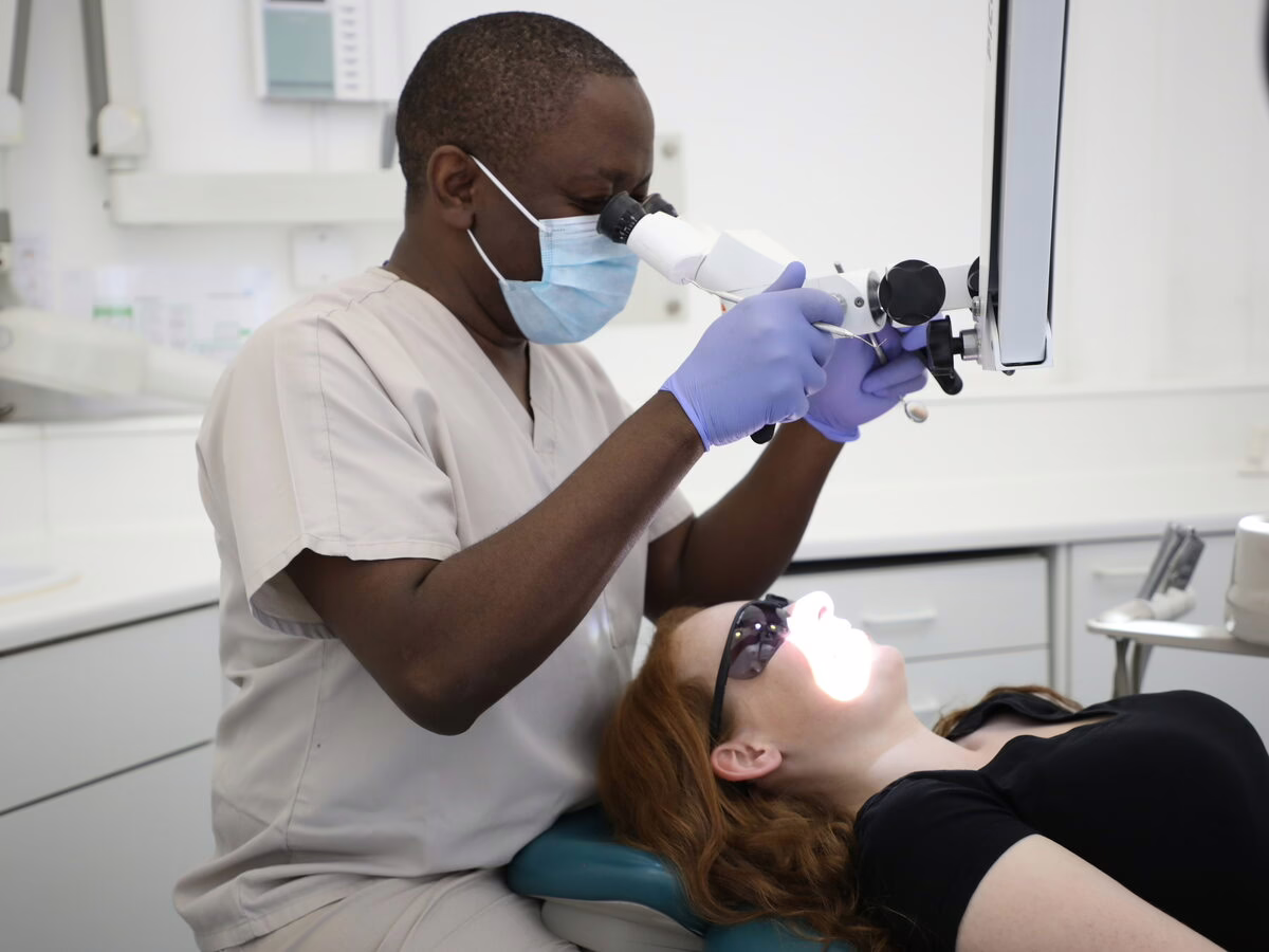 Dr Ope Sodeinde treating a patient with magnification