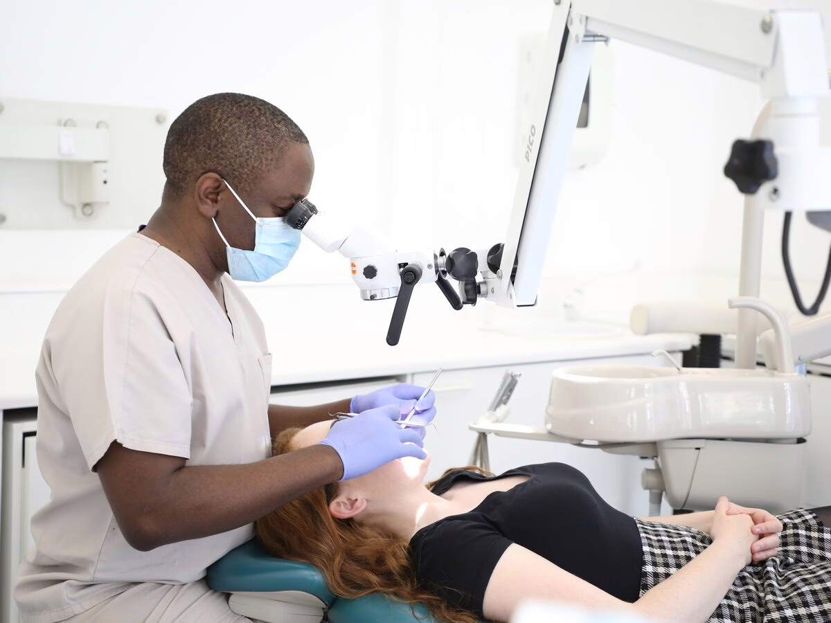 Dr Ope Sodeinde treating a patient with magnification