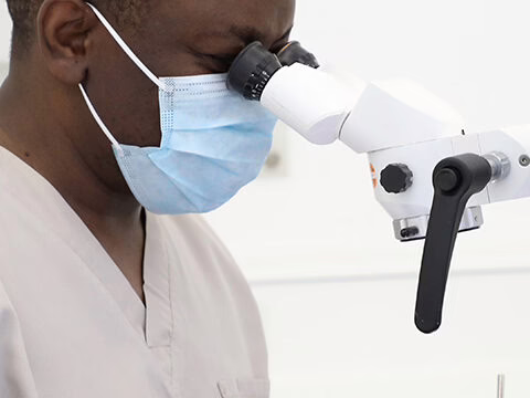 Dr Ope Sodeinde treating a patient with magnification