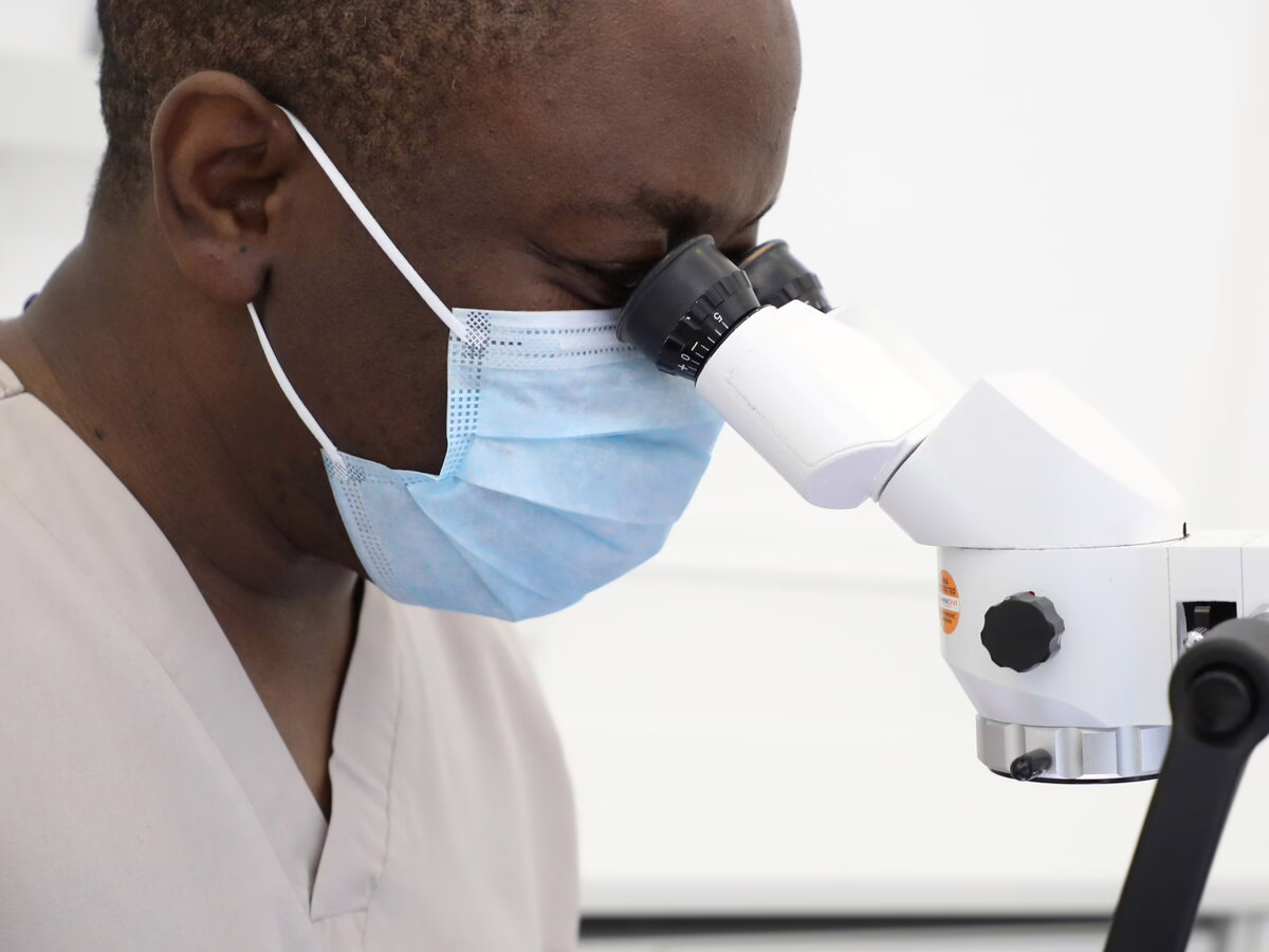 Dr Ope Sodeinde working at the operating microscope