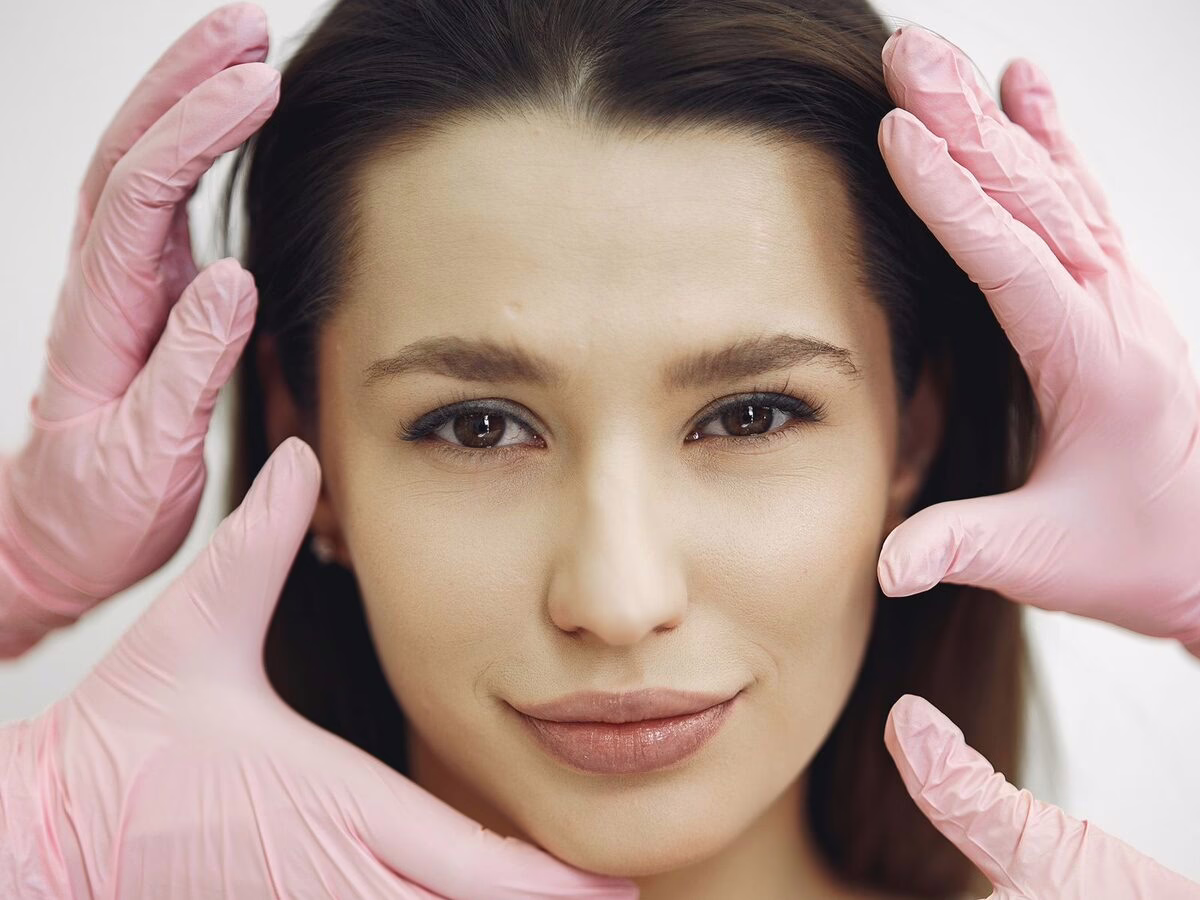 Gloved hands framing a face during a facial assessment