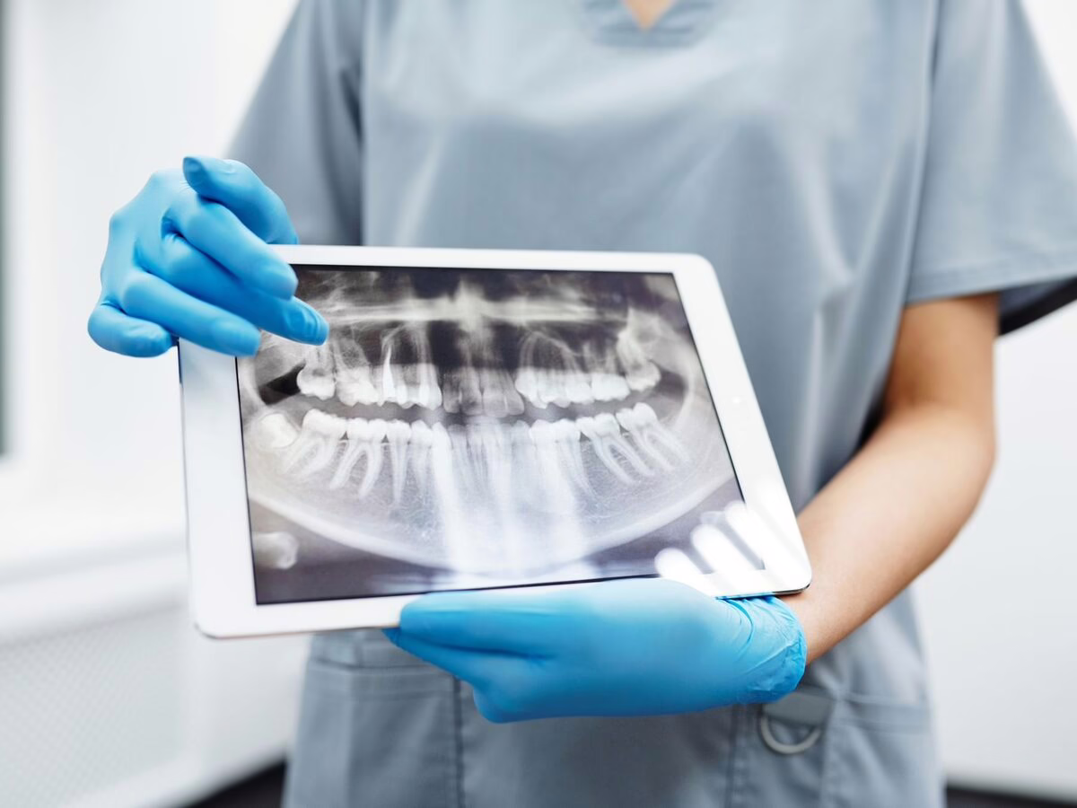 A clinician holding a tablet showing a panoramic x-ray